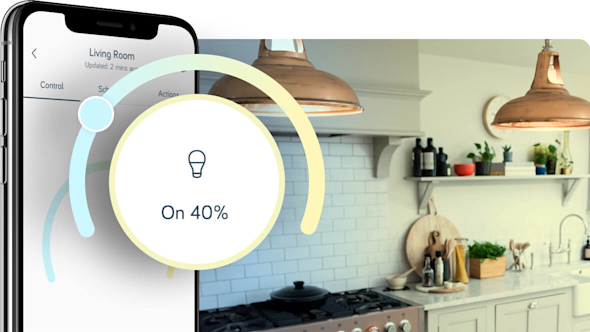 Side angle of smartphone showing the Hive app with a pop-out icon on the left of the image showing the Hive bulb tone set-up, with hanging lights in a kitchen in the background image