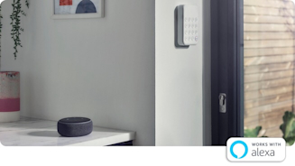 Grey kitchen with a Hive Keypad on the wall next to a black framed patio door and an Amazon Echo Dot speaker sitting on a white marble kitchen counter next to the wall with a framed picture