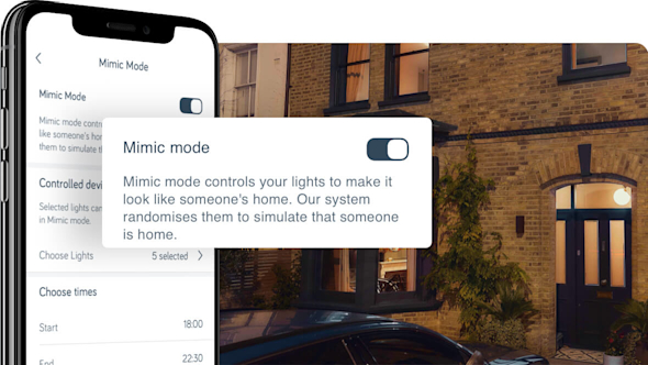 Side angle of smartphone showing Hive app with a pop-out screen in the middle of the image showing Hive bulb mimic mode set-up, with a brown brick house at night in the background image
