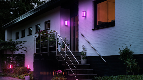 Outside of house at night with stairs leading up to a front door and purple lights attached to the walls