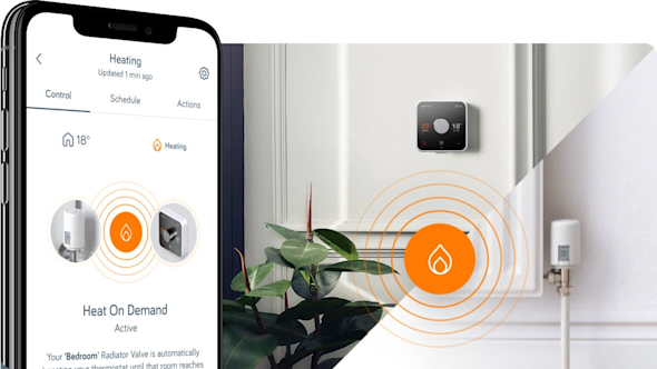 Side angle of smartphone showing the Hive app and an orange icon in the middle of the image showing a flame, with a Hive Thermostat attached to a wall and a radiator valve showing in the background image