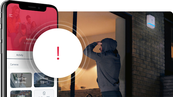 An image of a man in a hoodie peering through garden glass patio doors at night with a smartphone showing the Hive app superimposed on the image to the left