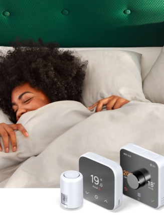 Women lying in bed with a duvet up to her face and a very green headboard in the background with Hive heating devices superimposed in the bottom right hand corner