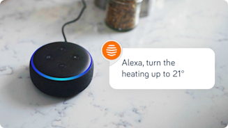 Close-up of an Amazon speaker sitting on a marble kitchen top with the phrase "Alexa, turn the heating up" superimposed to the right of the image