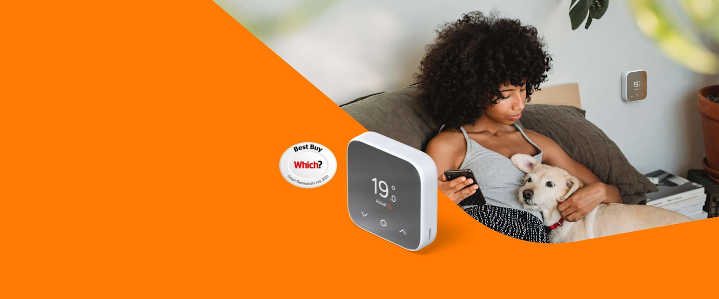 Woman sitting on a dark grey sofa cuddling a small dog in one hand and holding a smartphone in her other hand, and a Hive Thermostat Mini attached to the grey painted wall in the background, with a superimposed orange block at the bottom of the image showing the Hive Thermostat Mini in isolation