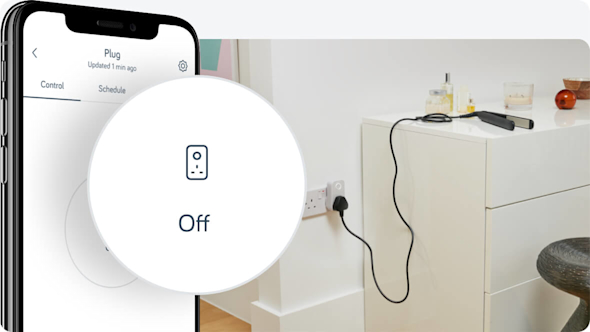 Side angle of smartphone showing Hive app with a pop-out icon showing an "Off" graphic, with hair straighteners lying on a white unit and connected to a Hive Active Plug in the wall socket
