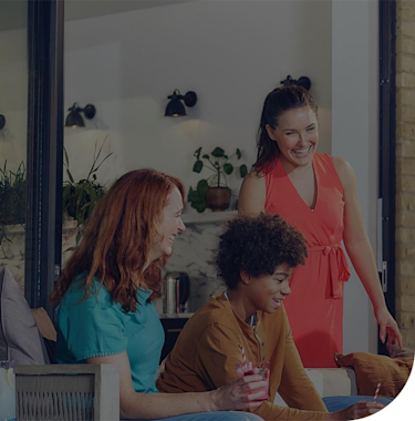 Family and friends sitting on sofas on a patio with large glass patio doors behind them next to a brick wall and dark wooden fence