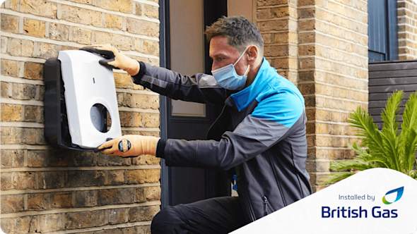 British Gas engineer installing a Hive EV Charger on the wall of a brown brick house with an Installed by British Gas logo in the bottom right corner