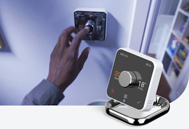 Man adjusting button on Hive Thermostat attached to a wall, with a Hive Thermostat superimposed in the bottom right corner
