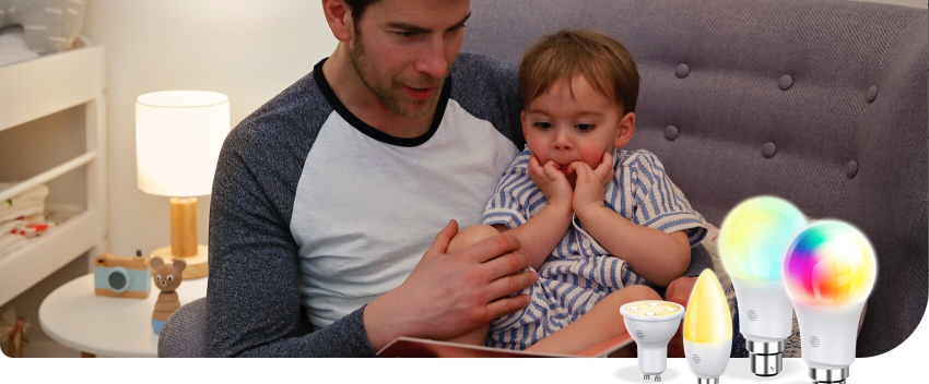 Young dad reading a book to his young son on a grey sofa and a table lamp and bed behind them, with a range of Hive smart lights bulbs superimposed in the bottom right corner
