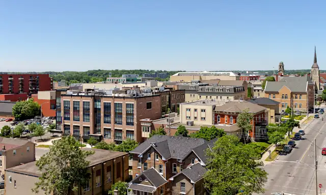 Cityscape of Brantford with historic buildings, tree-lined streets, and a church steeple in the background.