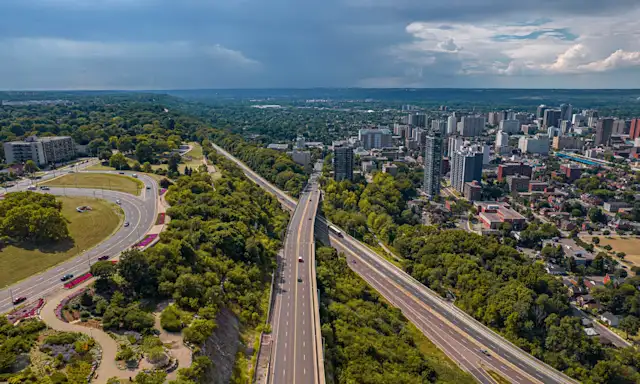 Aerial view of Hamilton, Ontario, showing the city's skyline, highways, and surrounding greenery.