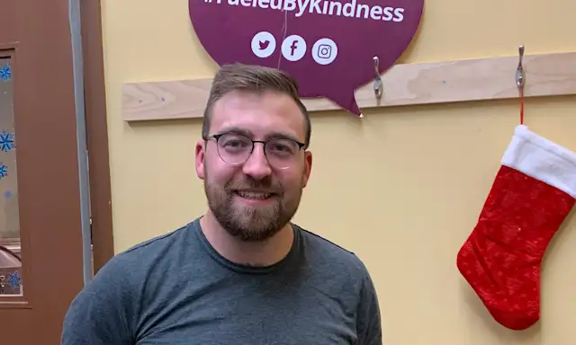 Man standing in front of a sign at Calgary Drop-In Centre.