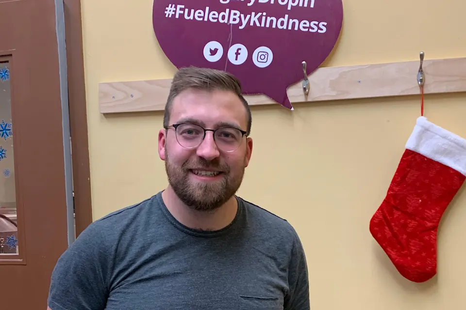 Man standing in front of a sign at Calgary Drop-In Centre.