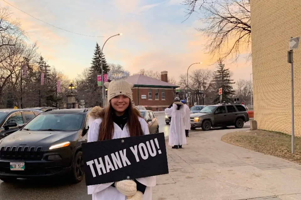 Person holding a 'Thank You!' sign on a sidewalk.