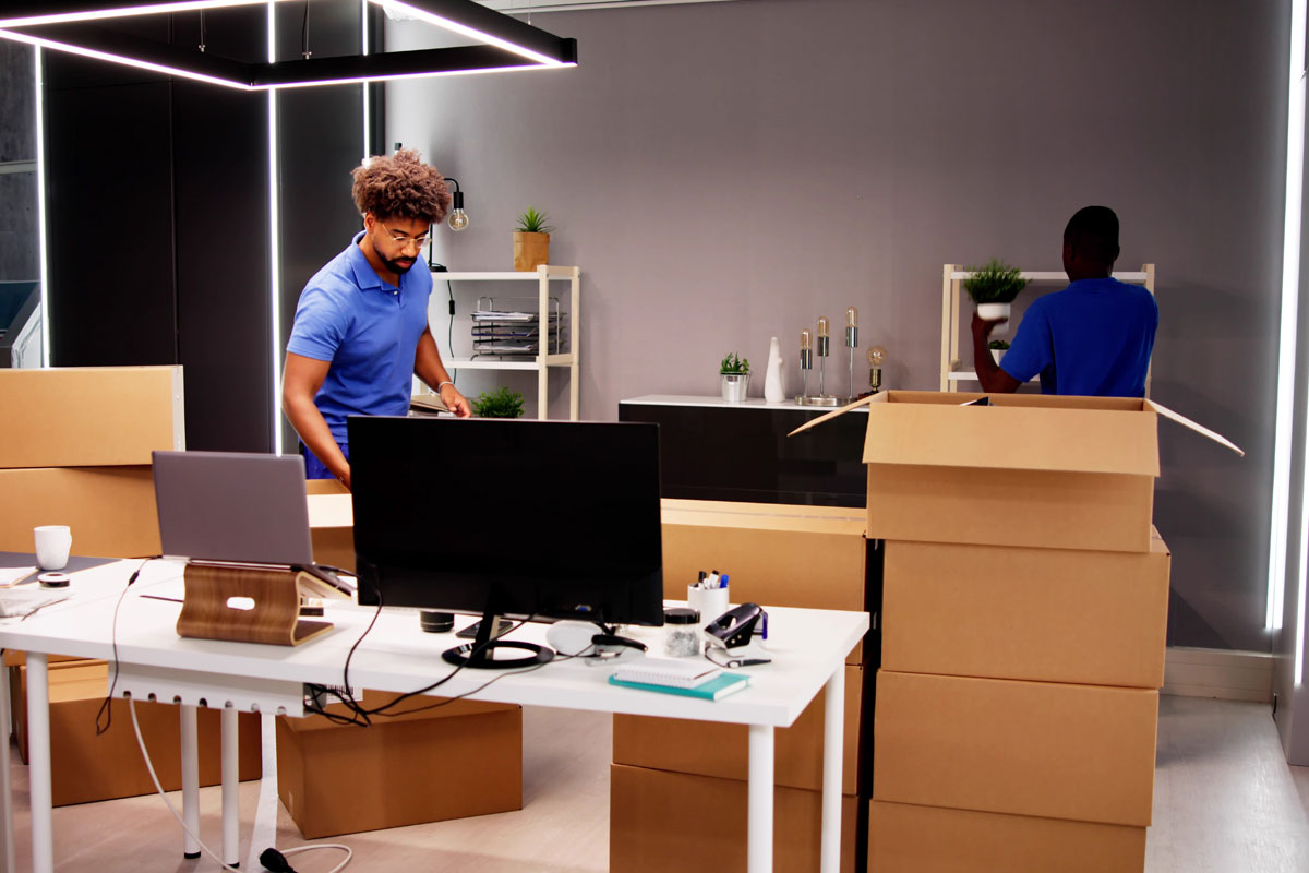 Movers packing boxes in an office setting.