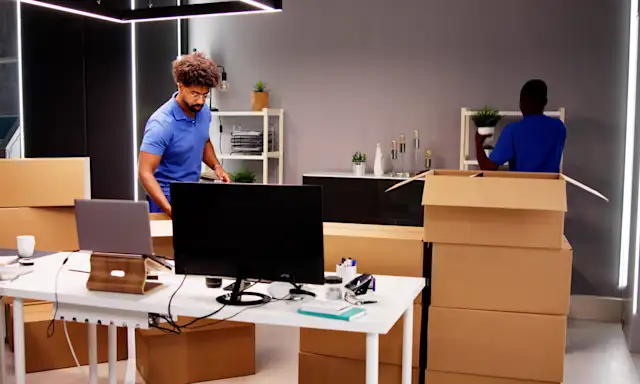 Movers packing boxes in an office setting.