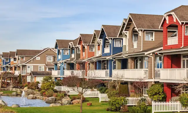 Colourful row of townhouses with white picket fences and landscaped gardens in Richmond, British Columbia.