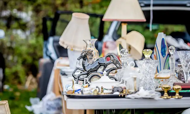 Assortment of household items, including lamps and decorative pieces, displayed on a table at a yard sale.