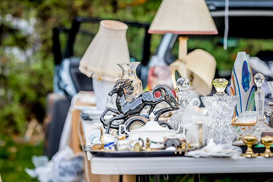 Assortment of household items, including lamps and decorative pieces, displayed on a table at a yard sale.