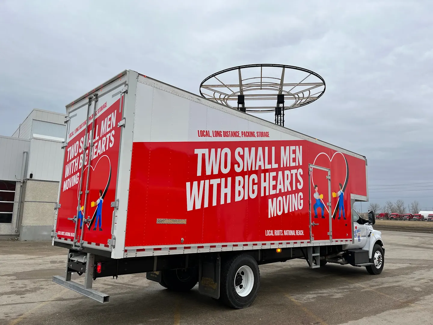 Red Two Small Men With Big Hearts moving truck parked in a lot, side view with the Local, Long Distance, Packing, Storage lettering