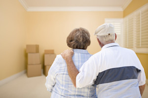 Senior couple looking at moving boxes in an empty room.