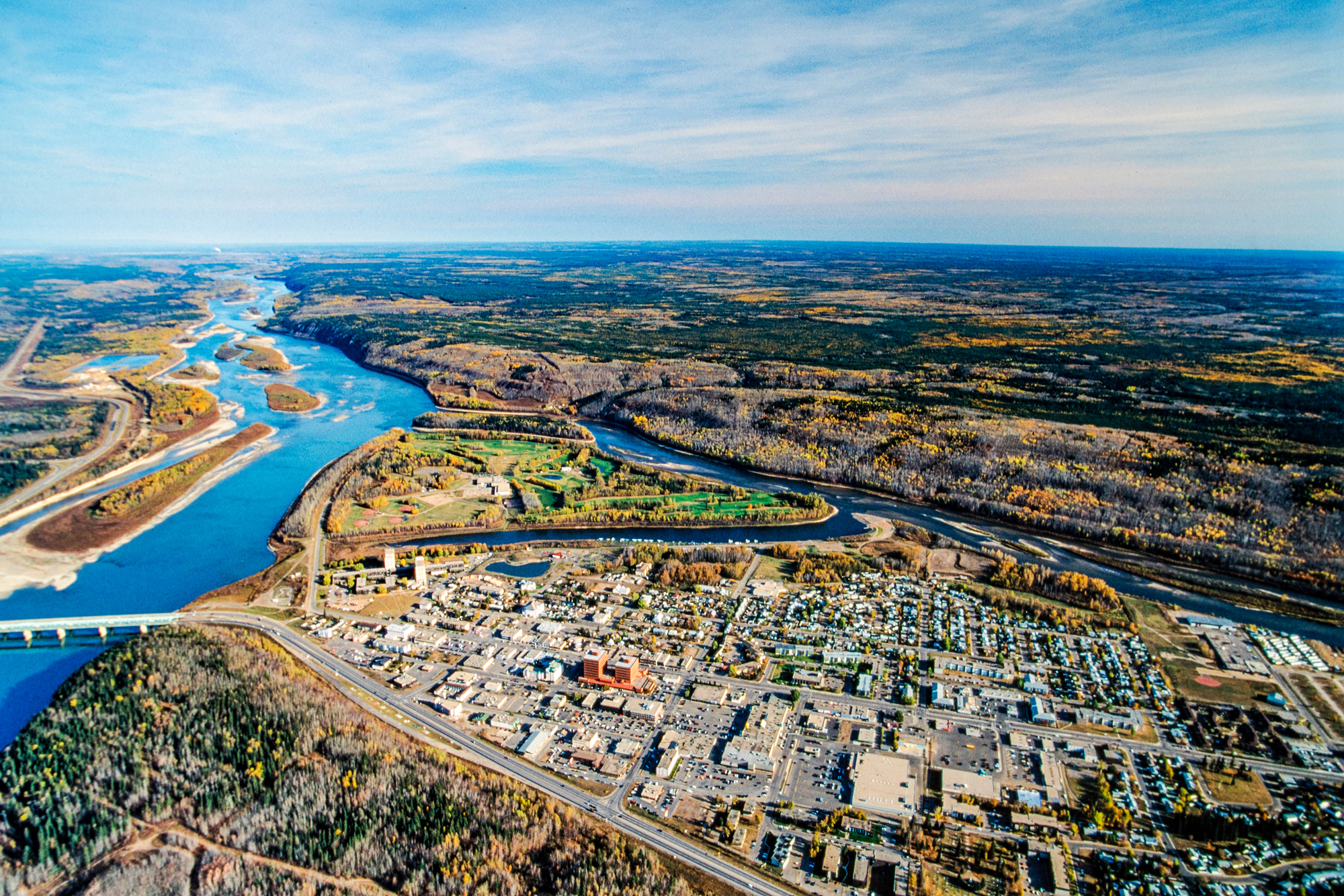 Aerial view of Fort McMurray with a river winding through the landscape and surrounding forested areas.
