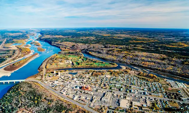 Aerial view of Fort McMurray with a river winding through the landscape and surrounding forested areas.