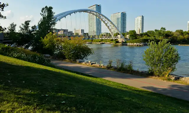 Humber Bay Arch Bridge over the Humber River with modern buildings in the background, viewed from Etobicoke, Toronto, Ontario.