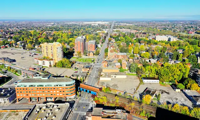 Aerial view of Brampton, showing streets, buildings, and green spaces extending into the distance.