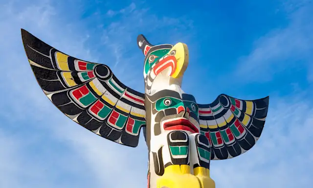Colourful totem pole in Duncan against a bright blue sky.