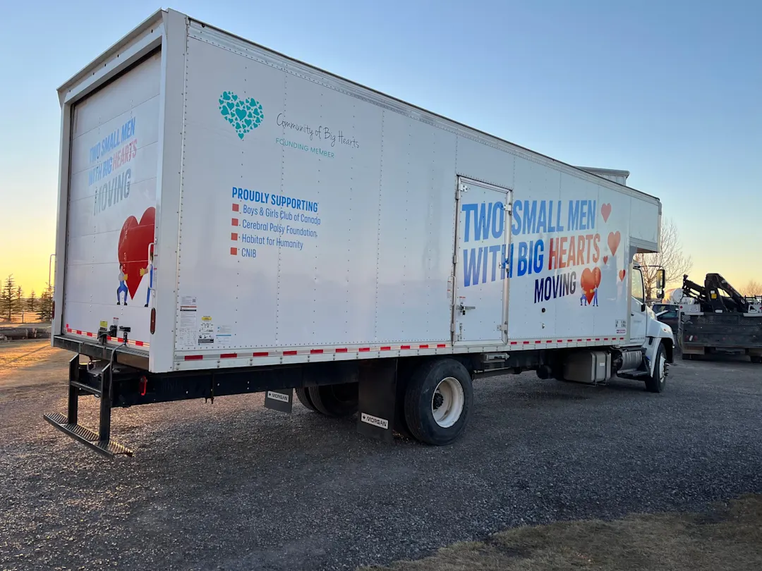 Two Small Men With Big Hearts moving truck at sunset with the Community of Big Hearts wrap listing the charities the company supports