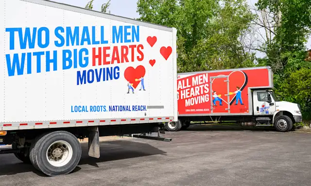 Two moving trucks from Two Small Men with Big Hearts Moving parked side by side.