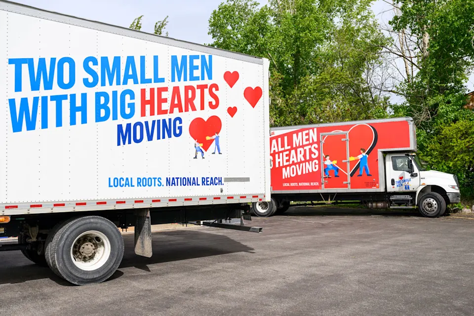 Two moving trucks from Two Small Men with Big Hearts Moving parked side by side.