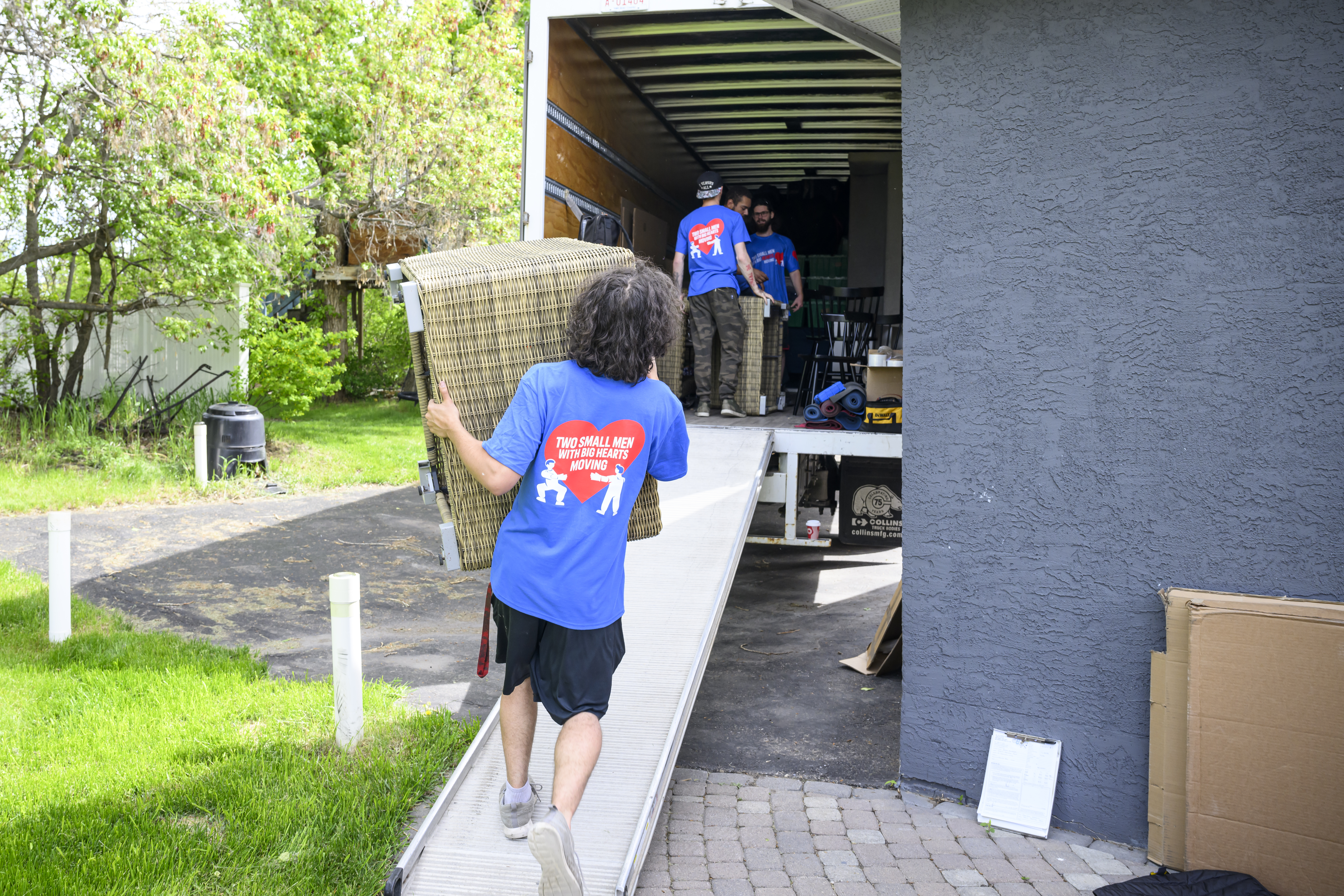 Movers in Two Small Men with Big Hearts Moving shirts loading a truck with furniture