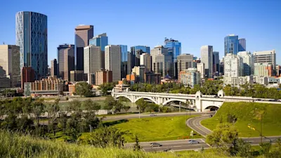 View of Calgary skyline with a bridge and green park in the foreground
