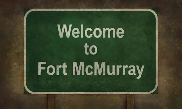 Welcome to Fort McMurray sign, featuring white text on a green background, with a weathered appearance.
