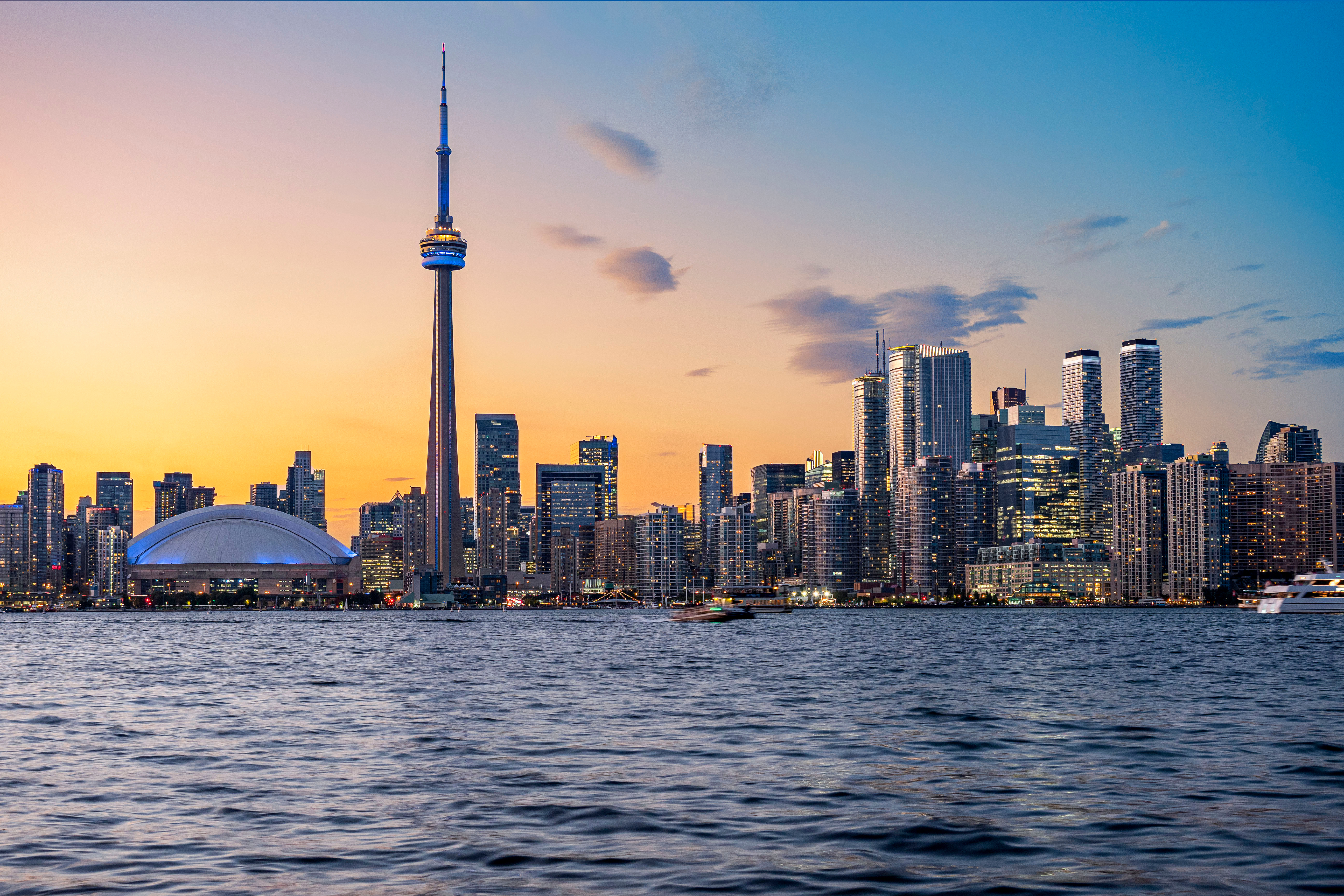 Toronto skyline at sunset featuring the CN Tower and Rogers Centre.