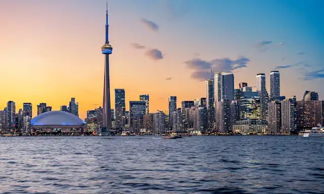 Toronto skyline at sunset featuring the CN Tower and Rogers Centre.