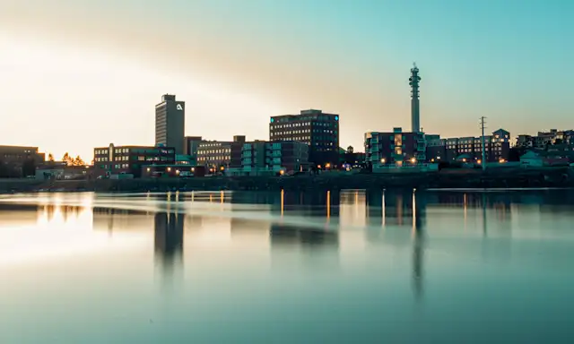 Cityscape of Moncton, New Brunswick, at sunset with reflections on the water.