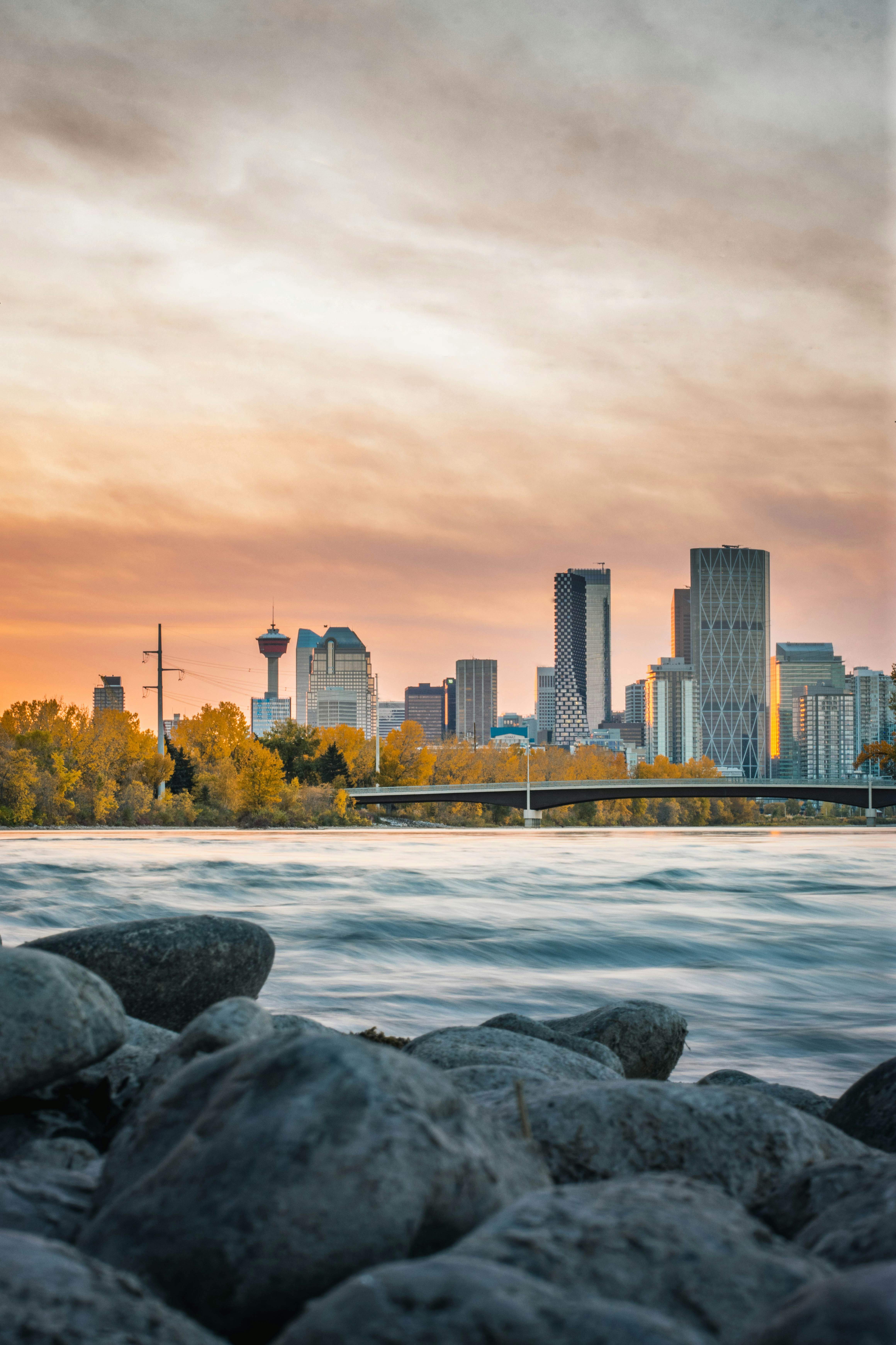 Calgary skyline at sunset viewed from a rocky riverbank