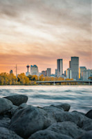 Calgary skyline at sunset viewed from a rocky riverbank