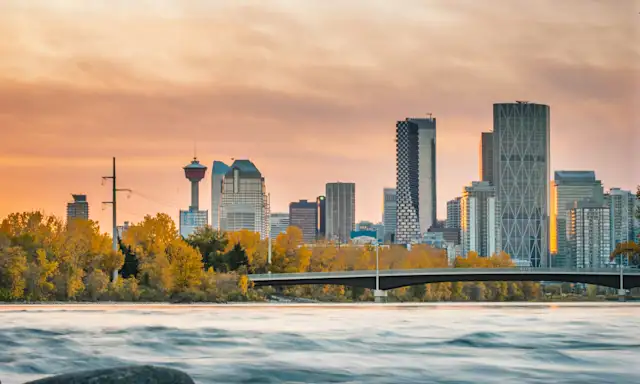Calgary skyline at sunset viewed from a rocky riverbank