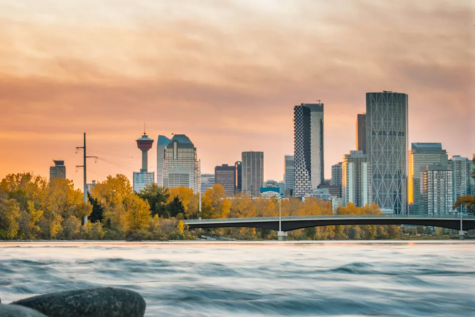 Calgary skyline at sunset viewed from a rocky riverbank