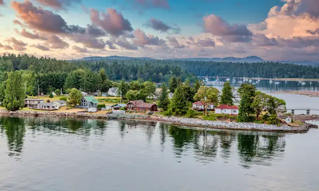 Coastal view of Nanaimo with houses along the shoreline, surrounded by trees and a calm body of water.