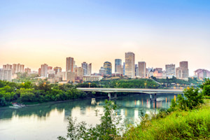 Edmonton city skyline at sunrise with the river and bridge in the foreground.