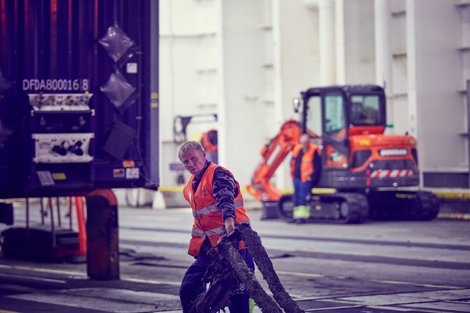 A DFDS Freight shipping employee handling ropes near the terminal