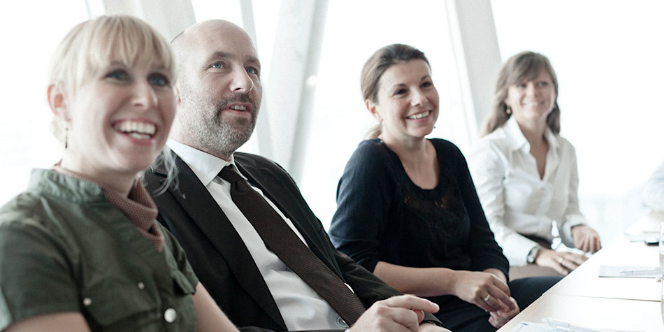 Four people smiling together at a meeting 