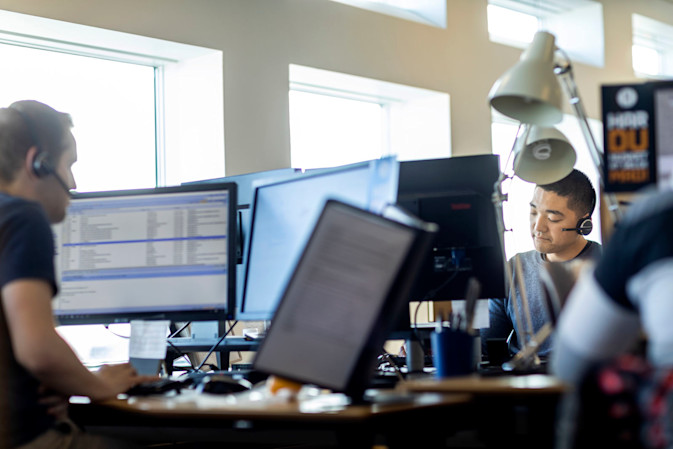 Two DFDS customer service representatives with headsets on, helping customers via phone
