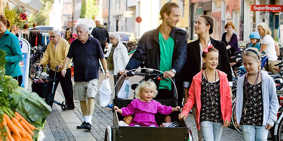 A family strolling down some cobbled, busy streets. 